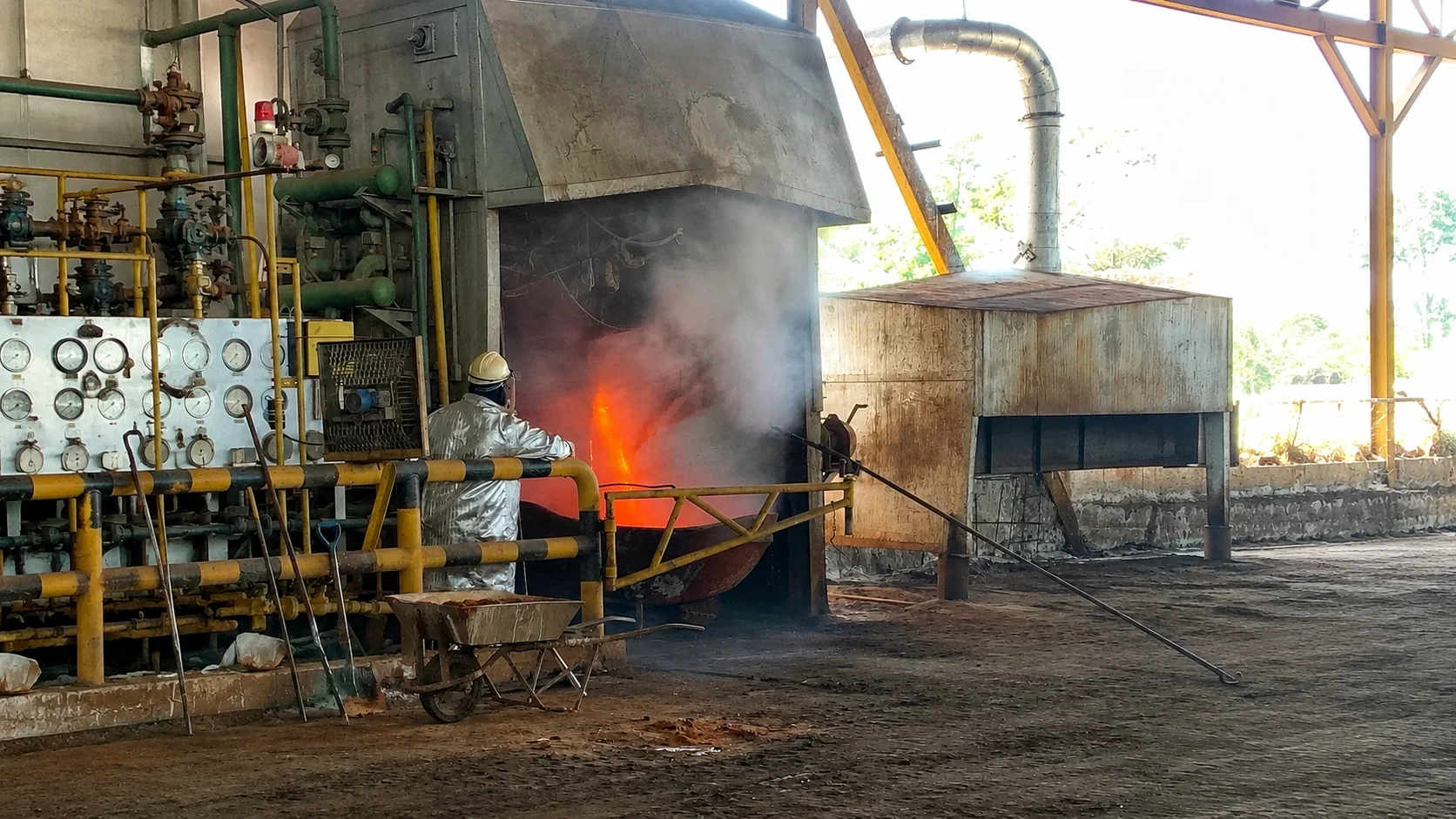 Operator in aluminized protective gear tapping molten lead at the FUNMETAL furnace